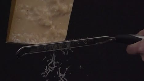 Parmesan torn on a grater in 500fps at black background