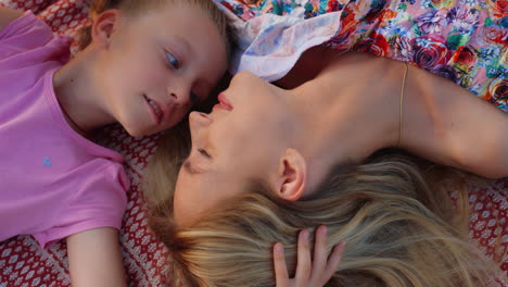 woman and girl nuzzling in garden. mother and daughter speaking at meadow.