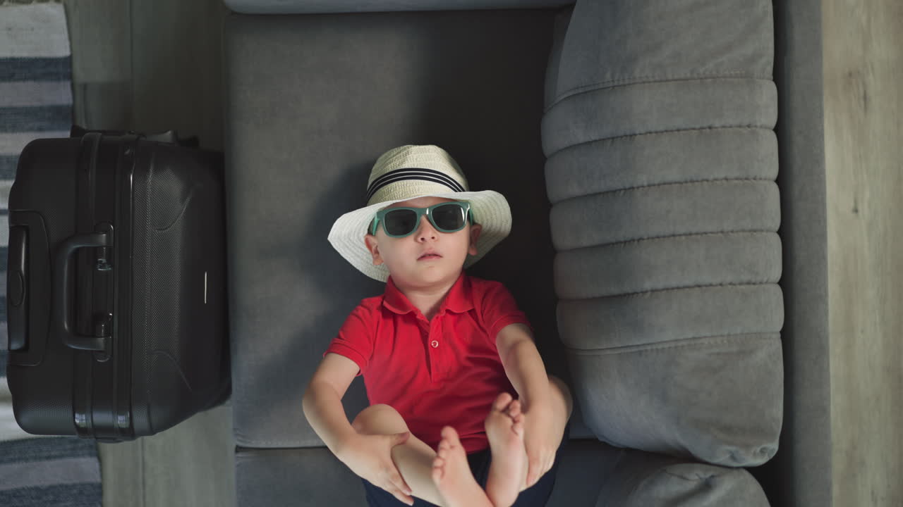 un niño relajado toca las piernas con las manos acostado en el sofá