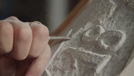 close-up view when a man engraving a stone surface with his hand as a type shape.