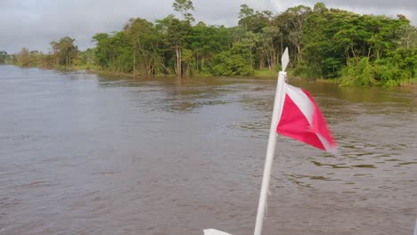 flag blowing in wind travelling along the amazon river