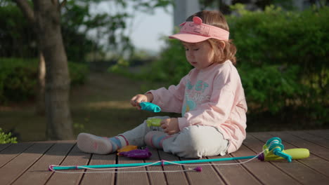 young girl playing with toy fishing set while sitting on deck