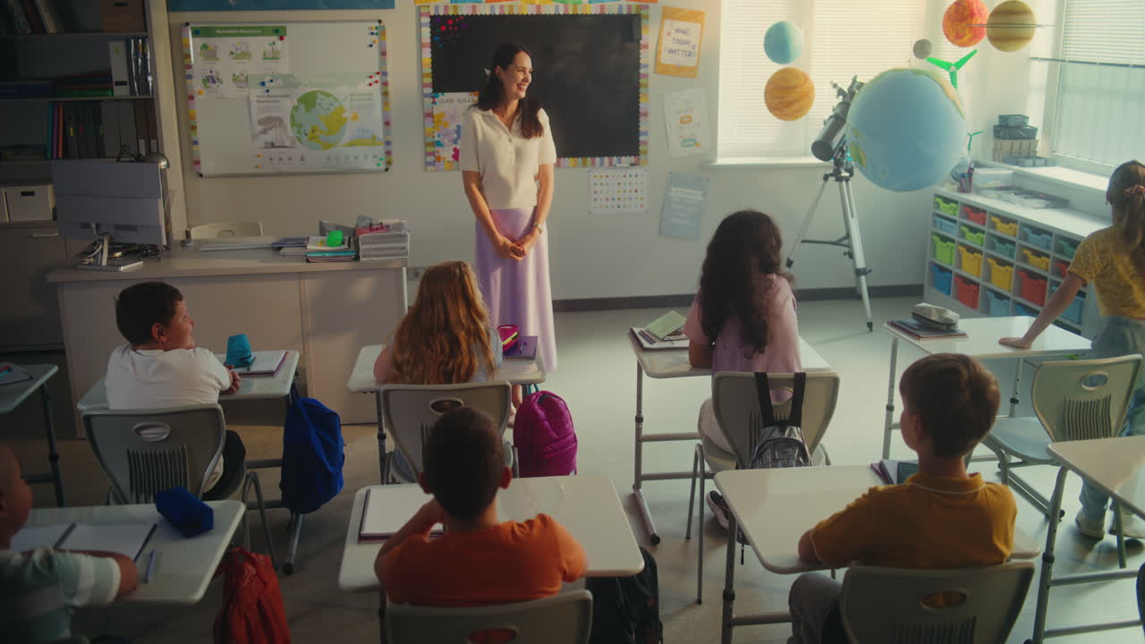 Primary School Children Sitting at the Desks Raising Hands to Give Correct Answer