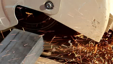 cut-off circular saw powers through a steel pipe, creating sparks