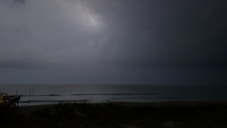 Thunder and lightning during a spring storm on the beach with a pier in the foreground