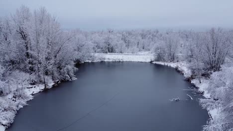 Imágenes-De-Drones-De-Un-Estanque-Cubierto-De-Hielo-Rodeado-De-árboles-Cubiertos-De-Nieve