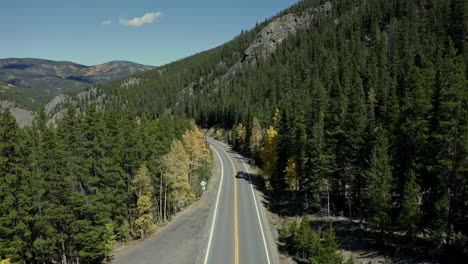 antena sobre la carretera del bosque de montaña mientras los autos pasan por debajo, paisaje al aire libre, 4k