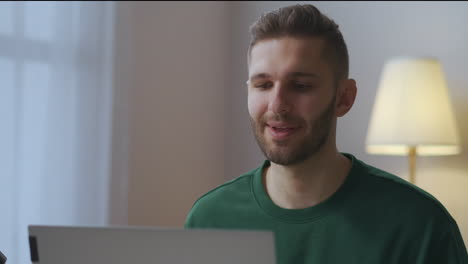 portrait-of-young-man-speaking-in-front-of-web-camera-of-laptop-webinar-or-online-meeting-with-partners-distant-communication-from-home-office