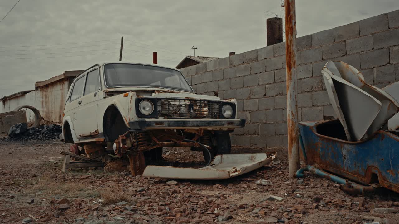 Chatarra de coche blanco oxidada y abandonada en un desguace