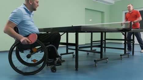 a man in a wheelchair plays ping pong. people with disabilities play table tennis. rehabilitation of the disabled. sport.