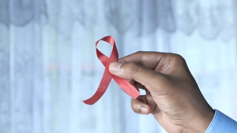 hand holding a red ribbon