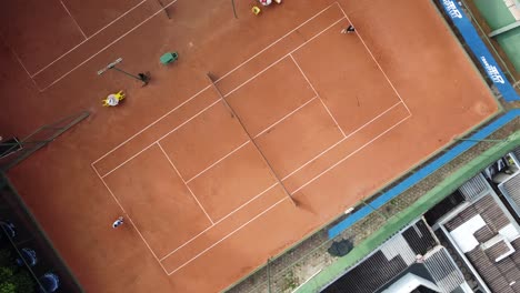 Espectáculo-De-Drones-A-Vista-De-Pájaro-De-Un-Partido-De-Tenis-En-Una-Cancha-De-Arcilla