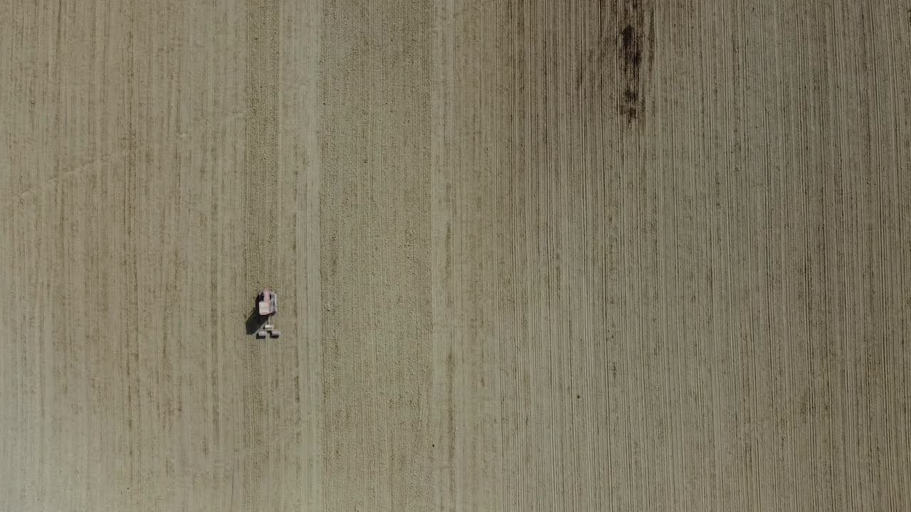 Aerial top down red tractor plowing organic soil in agricultural farm, minimalist drone view