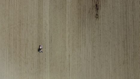 aerial top down red tractor plowing organic soil in agricultural farm, minimalist drone view
