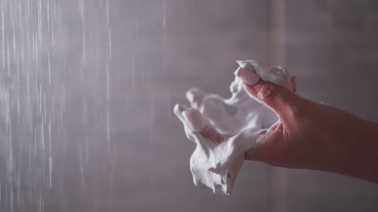 여성은 화장실에서 손바닥으로 몸 모스를 러. 여자의 손은 샤워실에서 피부 관리 부드러운 거품을 채찍질합니다. 스파에 대한 유기 화장품 제품