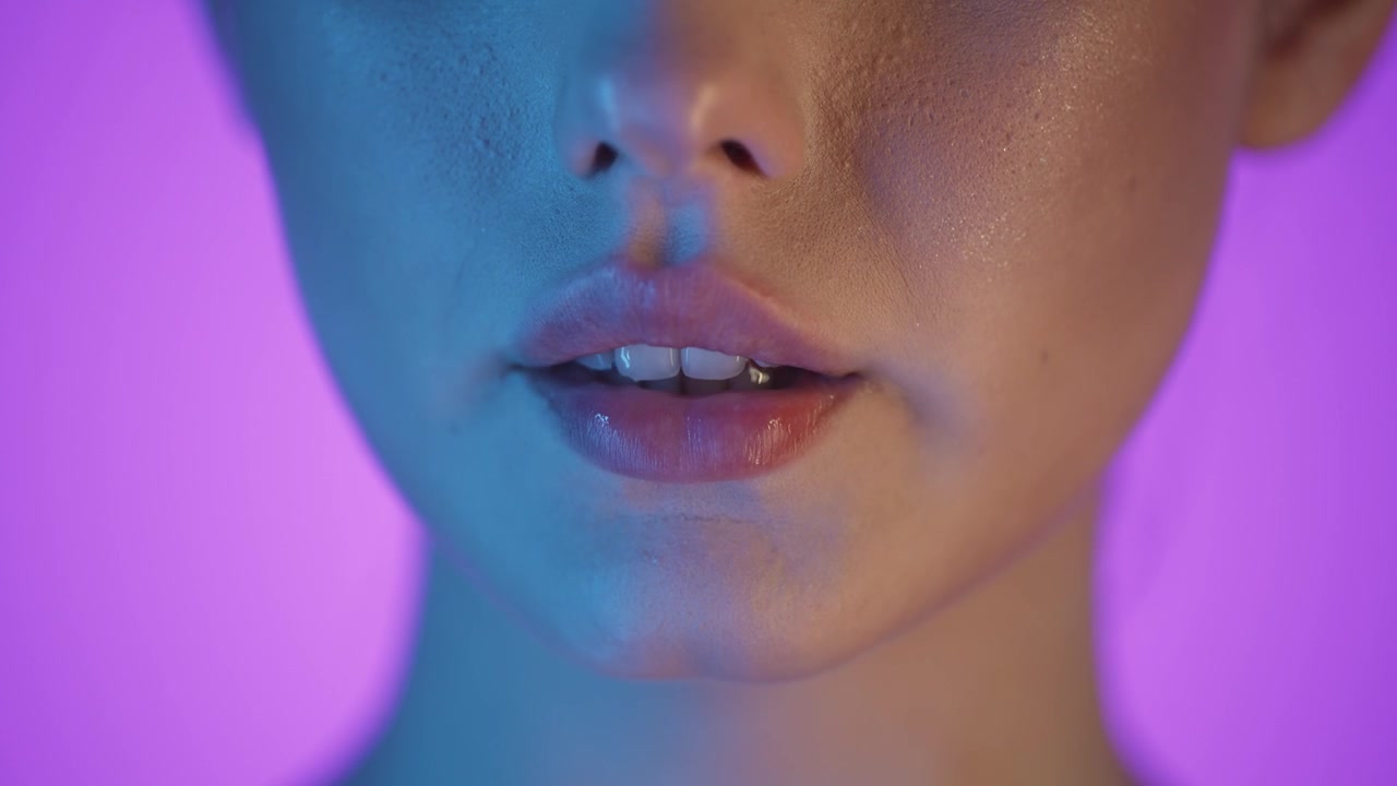 Ripresa macro 4K al rallentatore di una donna che beve acqua pura da un bicchiere trasparente, sfondo viola vibrante con illuminazione soffusa blu e rosa sul suo viso, estetica cinematografica e rinfrescante, primo piano