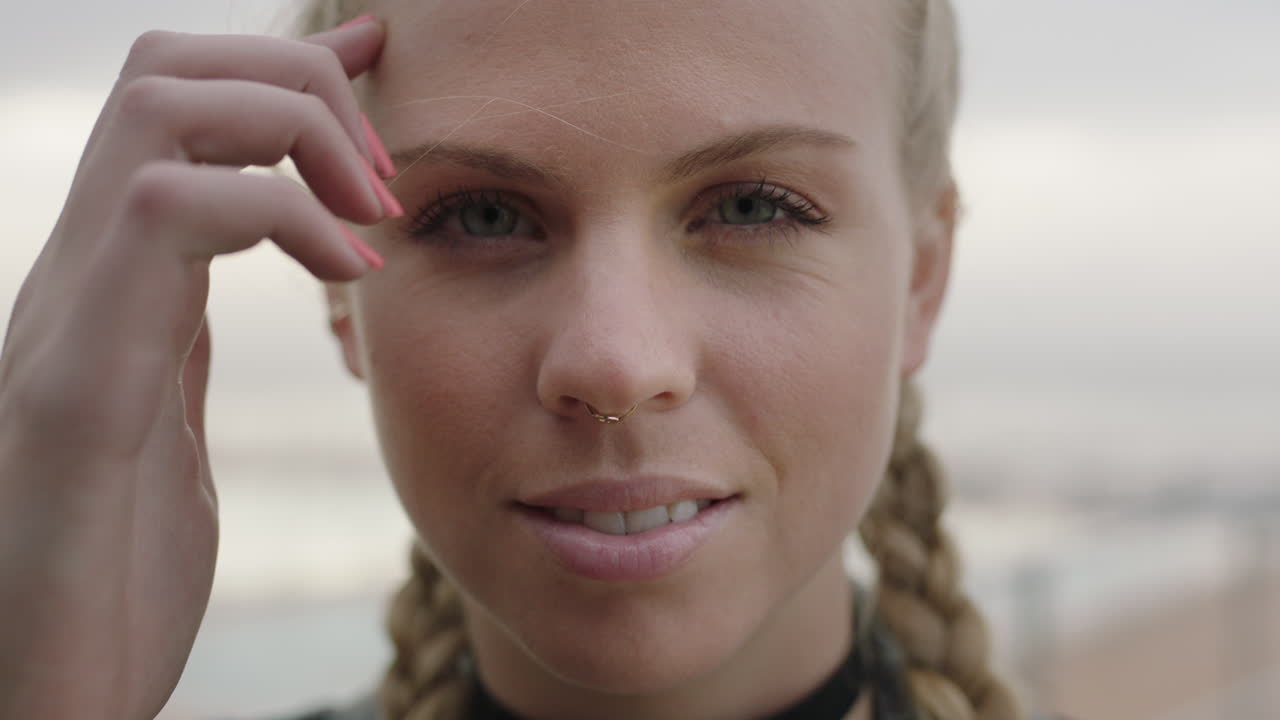 retrato de cerca de una atractiva mujer rubia que corre de la mano a través del cabello sonriendo con confianza