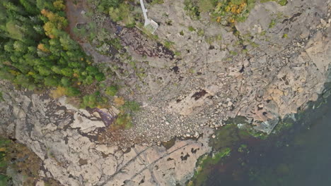 Top-View-Of-Autumnal-Forest-At-The-Rocky-Shore-Of-Calm-Sea-In-Sweden