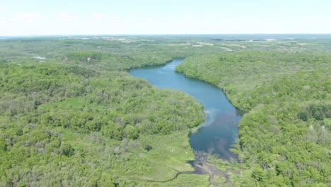 una toma ligeramente inclinada hacia abajo de un lago en medio de un denso paisaje forestal en las montañas de wisconsin, estados unidos