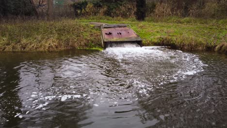 Wasserverschmutzung,-Fabrikabwasser,-Das-Aus-Rostigem-Betonrohr-Auf-Den-See-Fällt---Drohnen-Dolly-Aufnahme