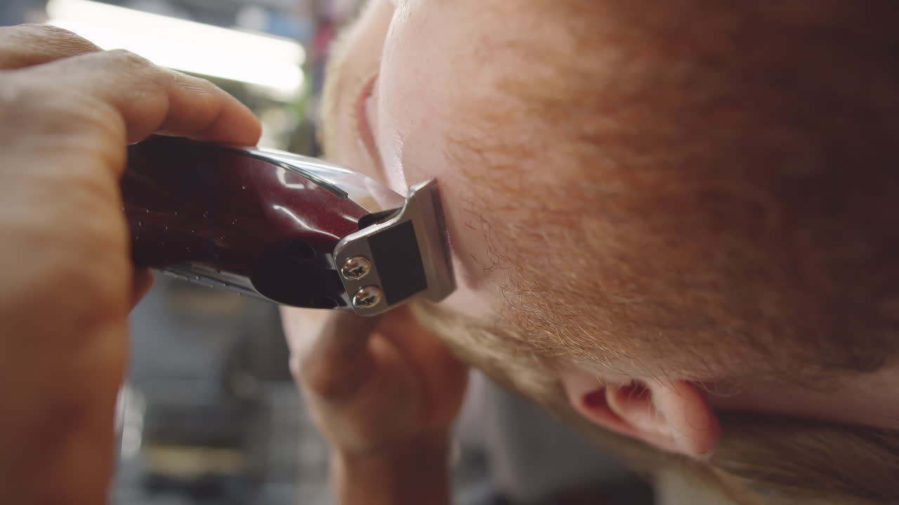 barbero usando un cortador para dar forma a la barba del cliente