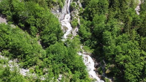 Forward-moving-aerial-showing-fresh-water-stream-flowing-in-the-middle-of-wilderness-with-hikers-and-trekkers-enjoying-the-rocky-terrain