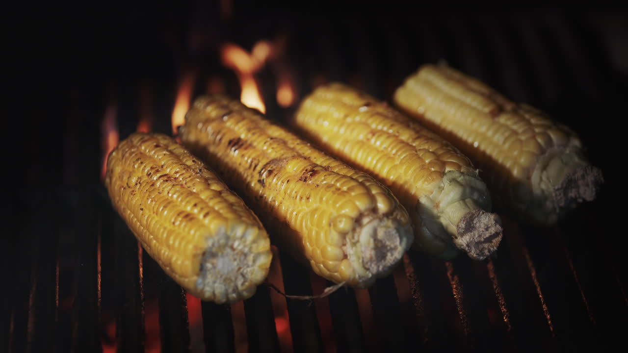 Four cobs of corn are fried on a hot grill grill
