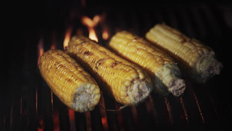 four cobs of corn are fried on a hot grill grill