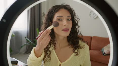 female beauty blogger recording makeup tutorial with ring light at home