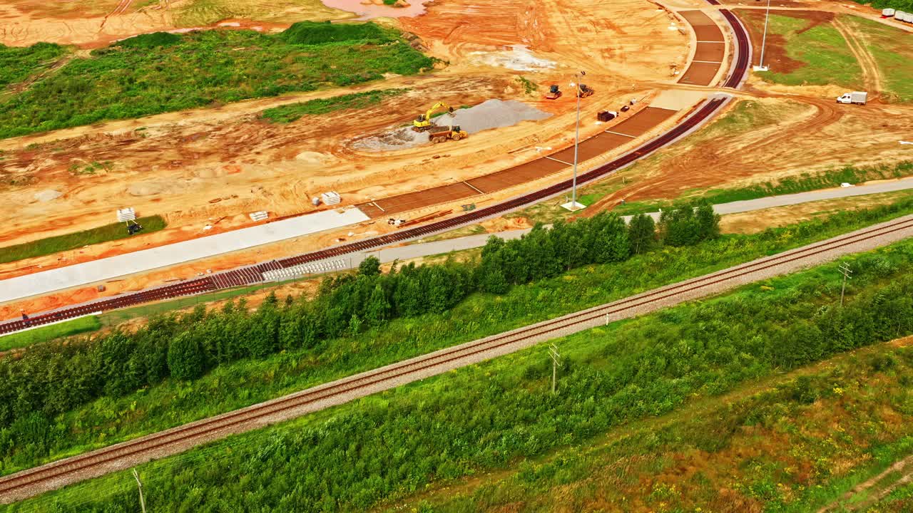 Aerial view of railway curve construction site with earthworks and trucks