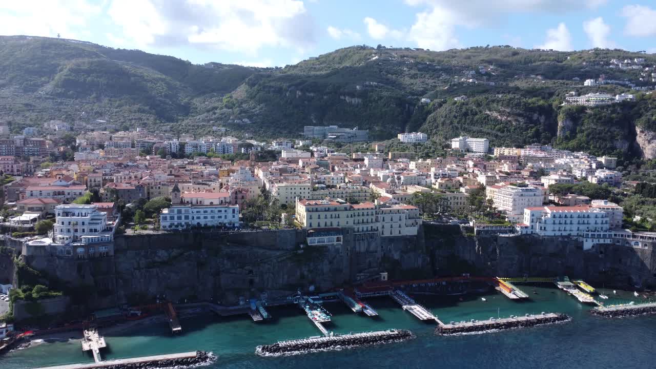 Waterfront buildings and cliffside port with water barriers in Sorrento, Italy