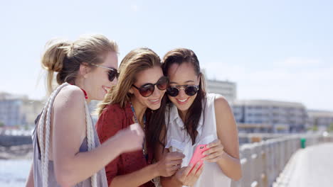 Group-of-Teenage-girls-taking-photo-using-mobile-phone-at-beach-on-summer-vacation--close-up