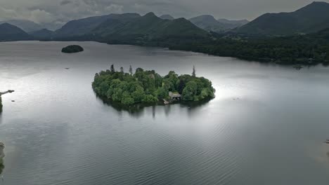 drone aerial footage of a island and house on derwentwater, keswick, a calm lake with river boats and a stormy sky