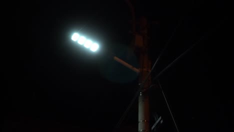 primer plano de un faro solar blanco que brilla en la calle por la noche en ausencia de la iluminación pública amarilla convencional que está rota y apagada