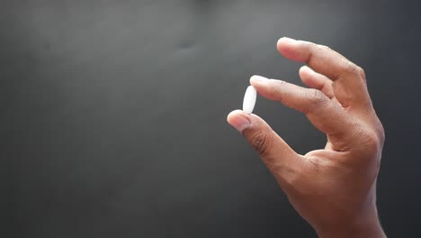 a hand holding a white pill