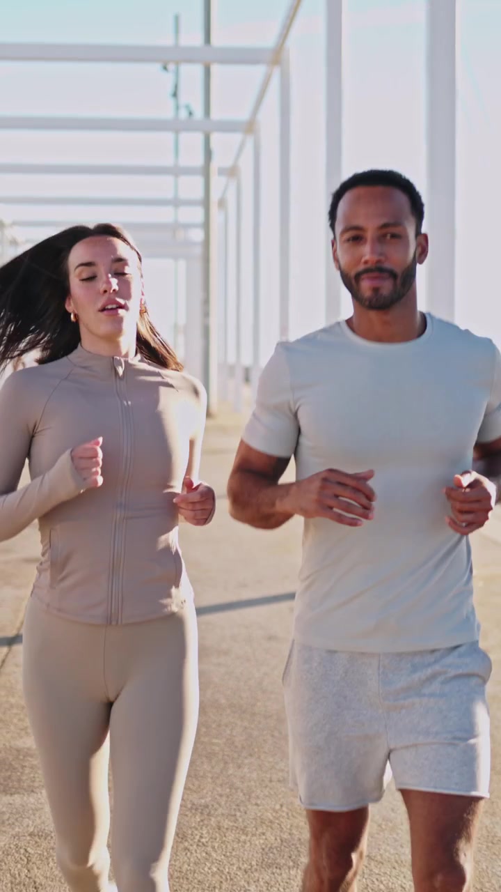 Giovane coppia che fa jogging insieme su un sentiero soleggiato all'aperto