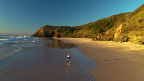 reveladora foto de un hombre caminando por una playa de arena con la cabeza rota cerca de byron bay