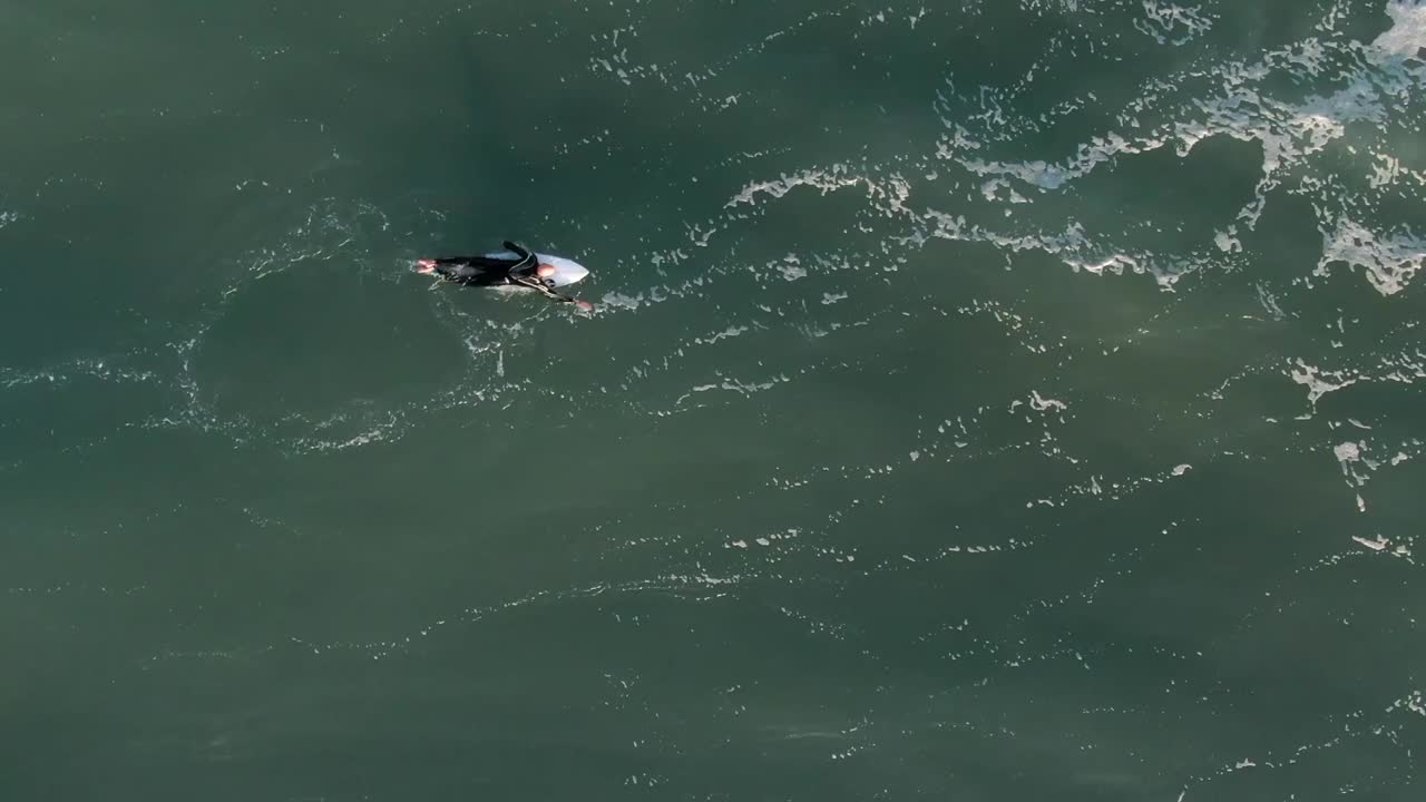 페루 리마의 라 팜필라 해변에서 파도를 향해 노를 젓는 서핑보드에 누워 있는 서퍼