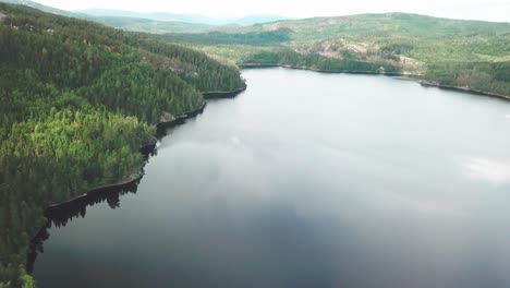 Movimiento-Lateral-De-Una-Toma-Aérea-Con-Una-Ligera-Inclinación-Hacia-Abajo-Sobre-Un-Lago-Rodeado-Por-Un-Bosque