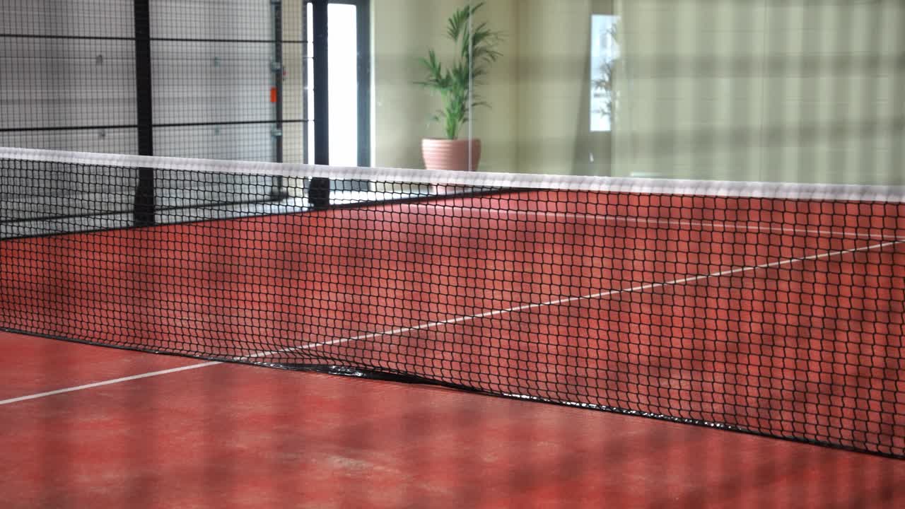 Clay padel court net indoors, focus on sport and quiet setting