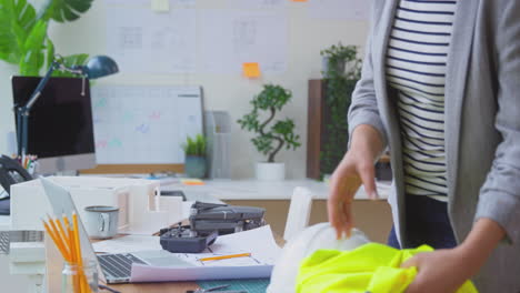 female architect in office at desk with drone working on plans for new building using laptop