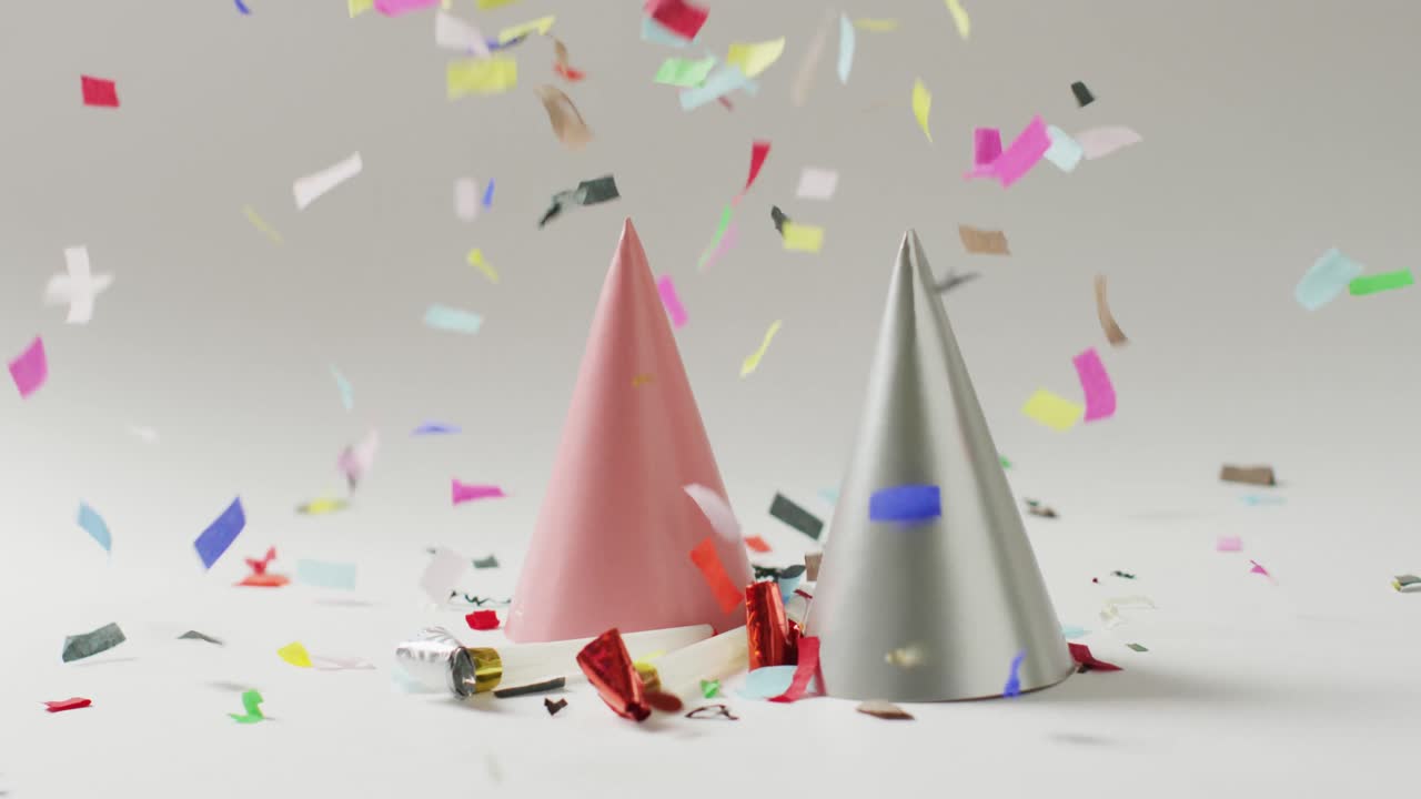 video de un sombrero de fiesta rosa y plateado con confeti colorido cayendo sobre un fondo gris pálido