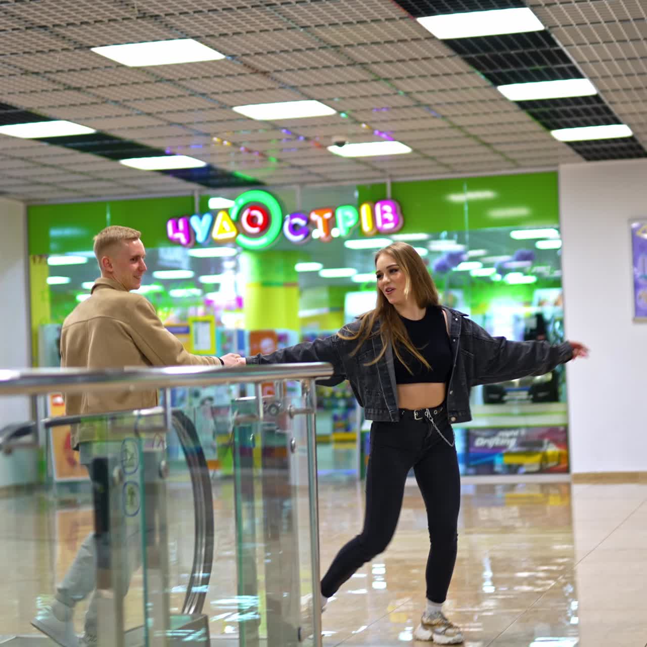 Energisk og glad pige, der danser og shopper med sin kæreste. Smukt par tilbringer fritiden sammen i et indkøbscenter