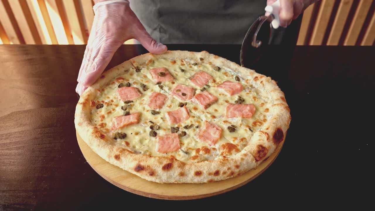 셰프는 둥근 커터로 신선하게 만든 피자를 잘라니다.