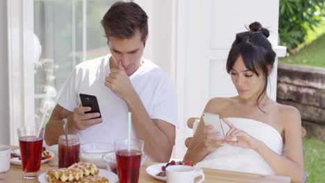 distracted couple using smart phones at table