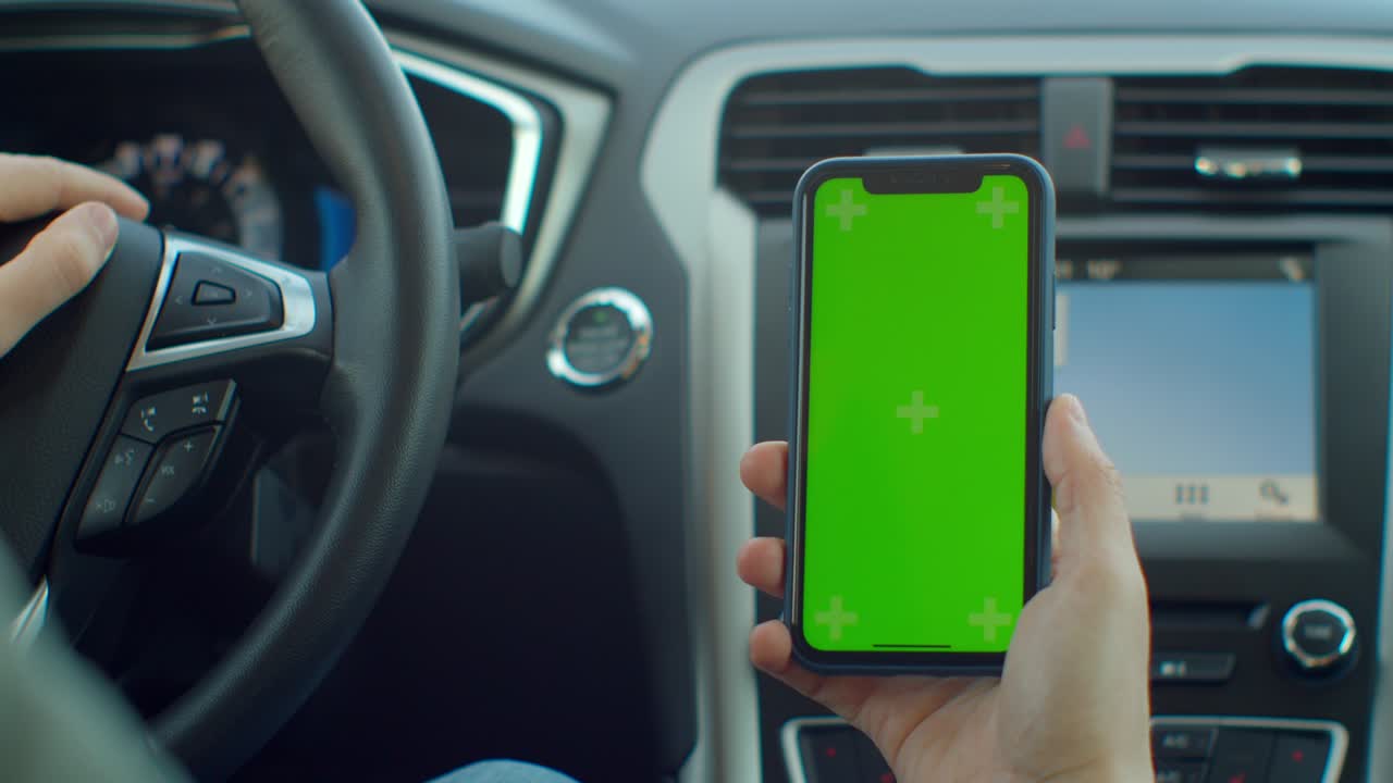 Man hand using chromakey mobile phone with empty green screen in modern car. Mockup touchscreen. internet searching.