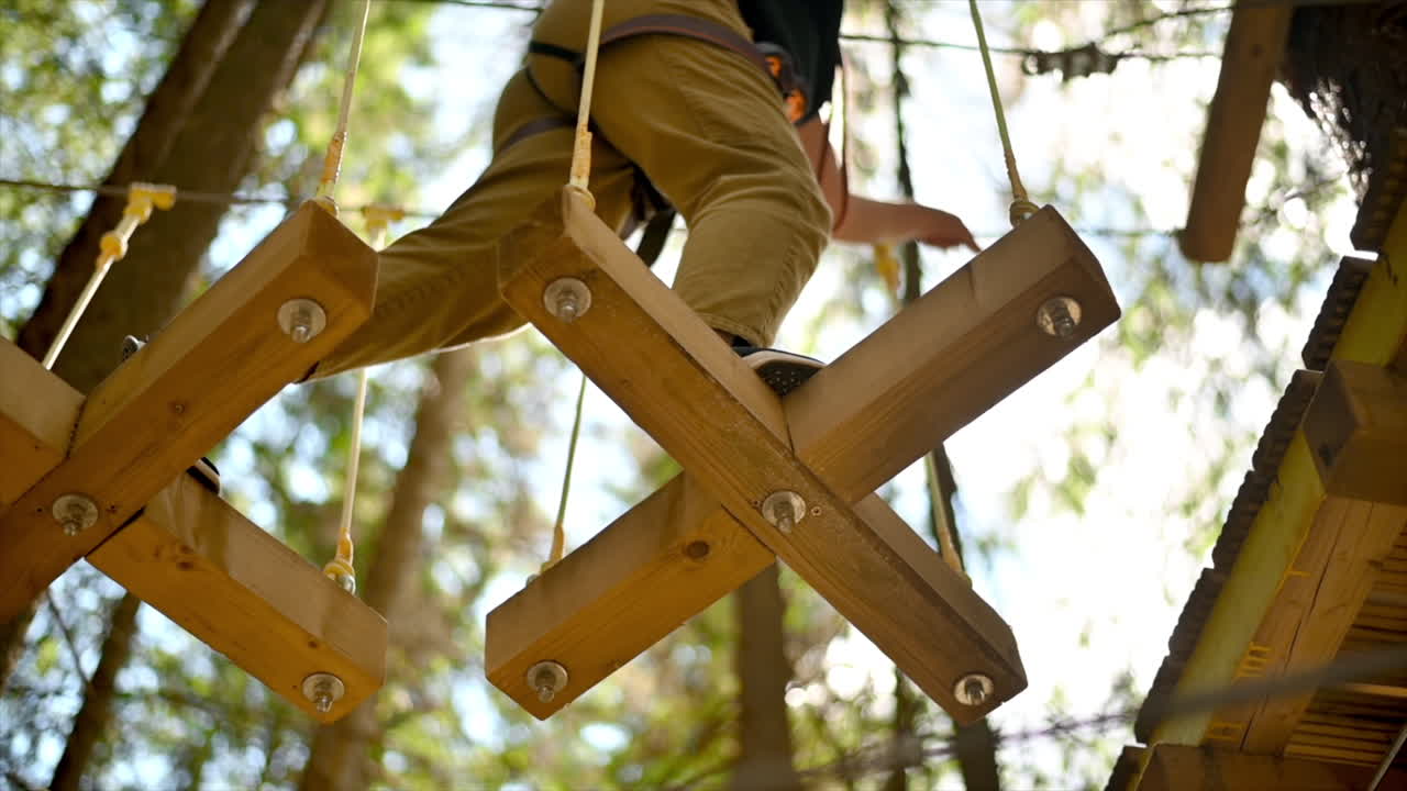 View of a man at climbing adventure park in the Carpathians, greenery around, Romania. Slow motion