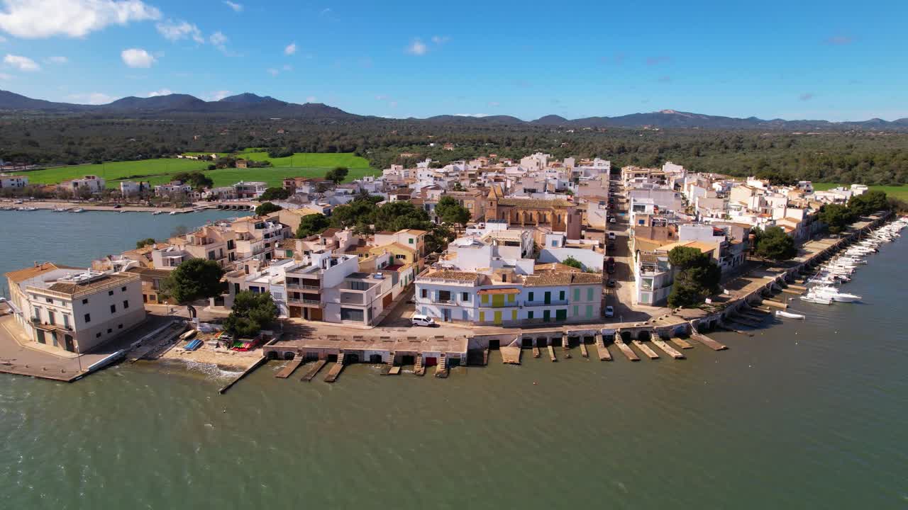 Houses built in typical Mallorcan architectural style directly adjacent to a harbor