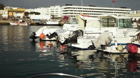 Point-of-view-sailing-through-a-fishing-harbour-with-many-boats-docked-on-water