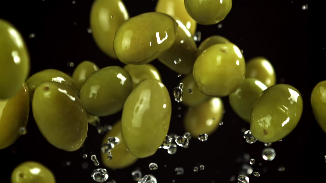 Olive verdi fresche in caduta al rallentatore con schizzi d'acqua